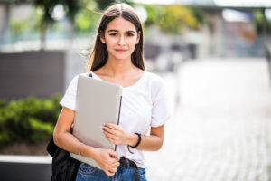 portrait of young happy blogger with modern laptop outdoors